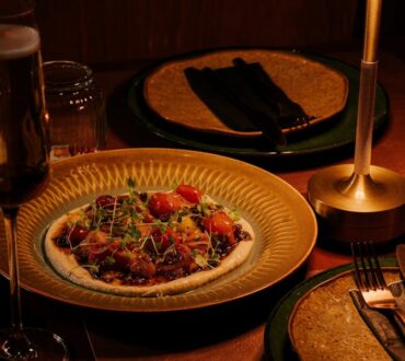 Plated heirloom tomato dish on a gold plate with a glass of sparkling wine