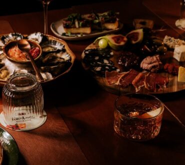 Dining table with fresh oysters, sliced steak and wine glasses